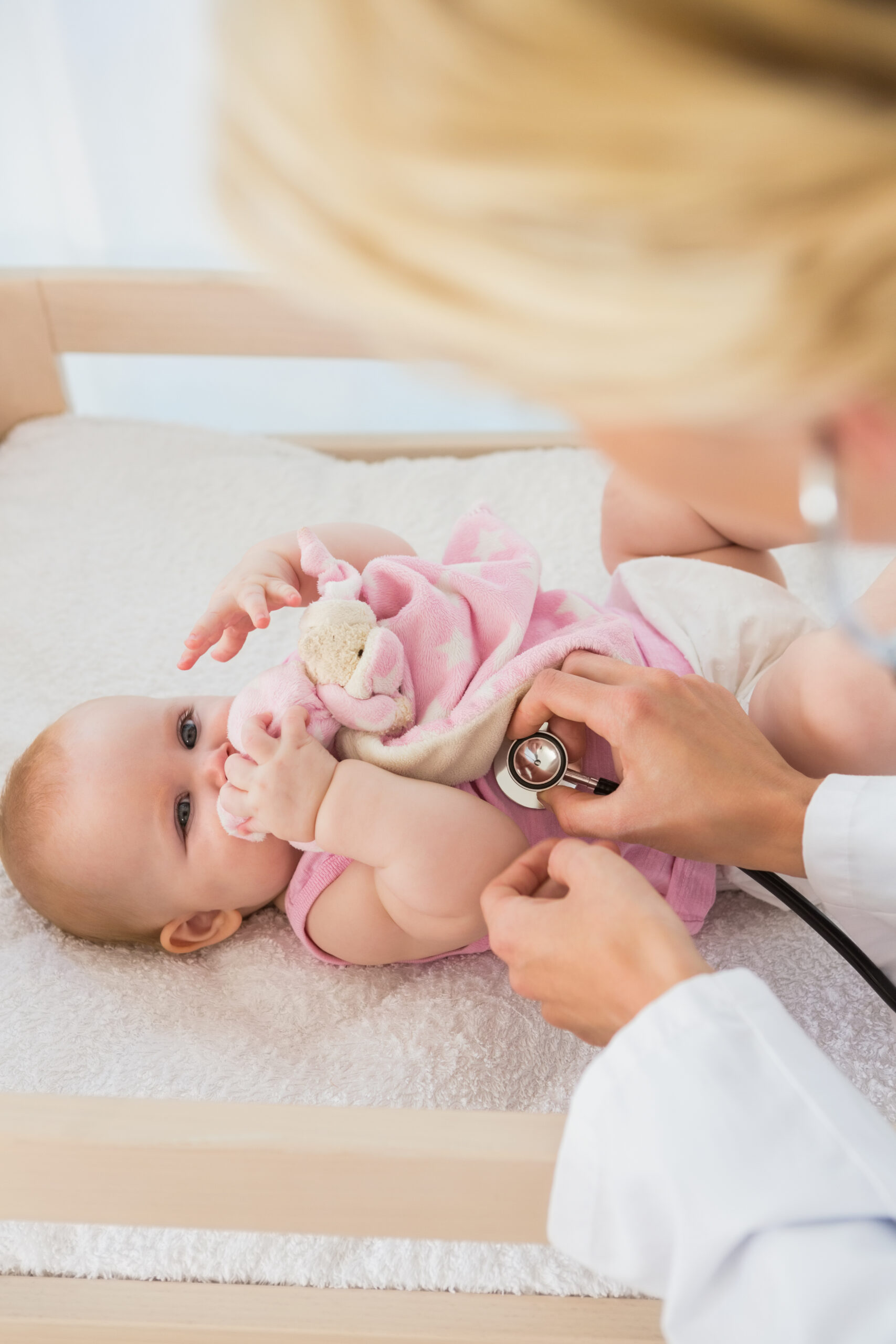 Beautiful cute baby girl with doctor with stethoscope at home in bedroom